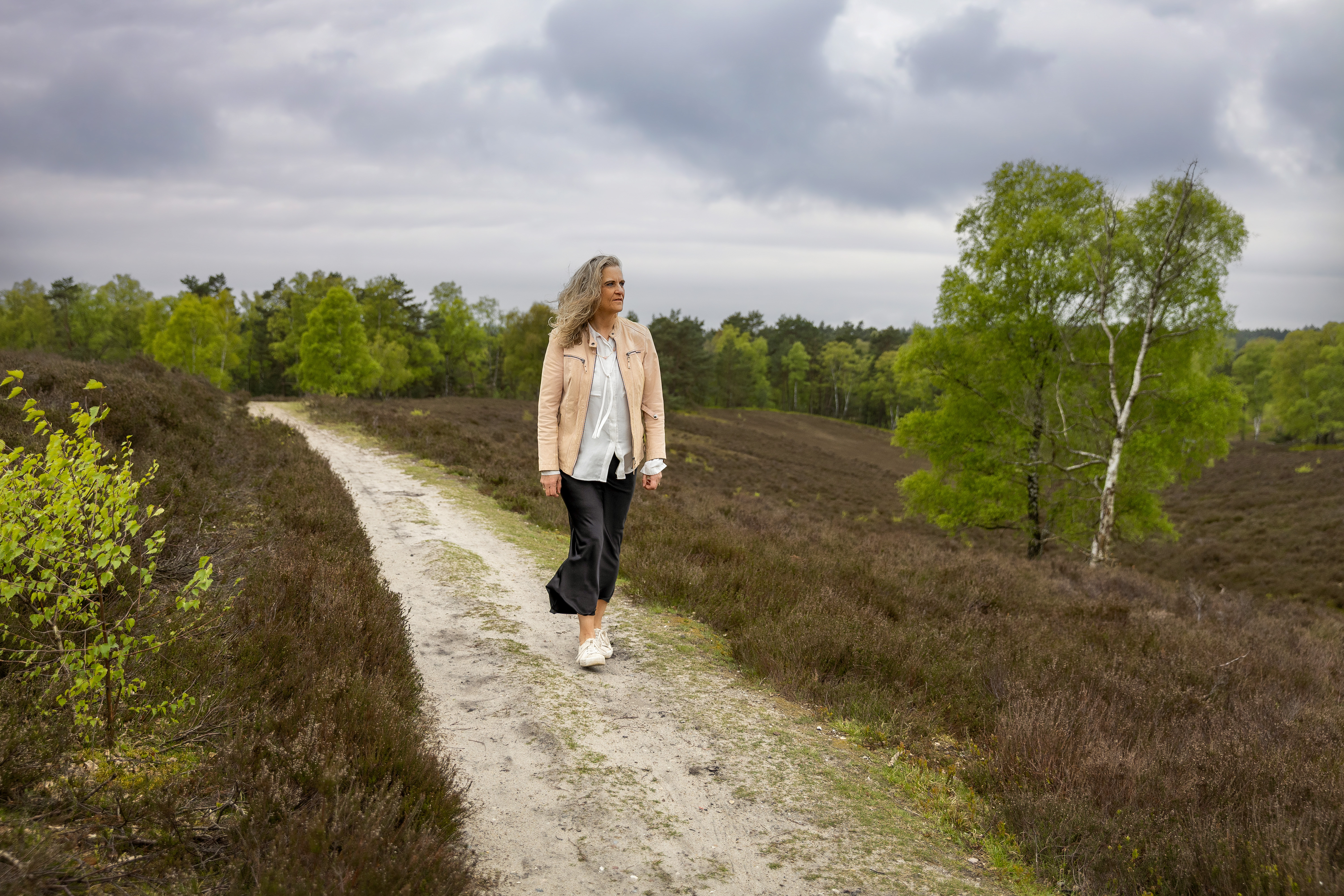 Britta Selina steht mit ausgebreiteten Armen in der Heide und blickt in die Weite