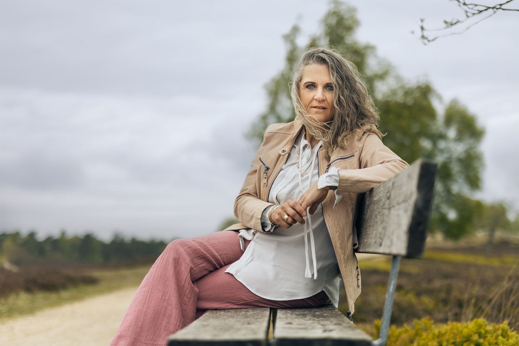 Porträt Britta Selina – Spiritual Life Coach, sitzt auf einer Bank in der Heide